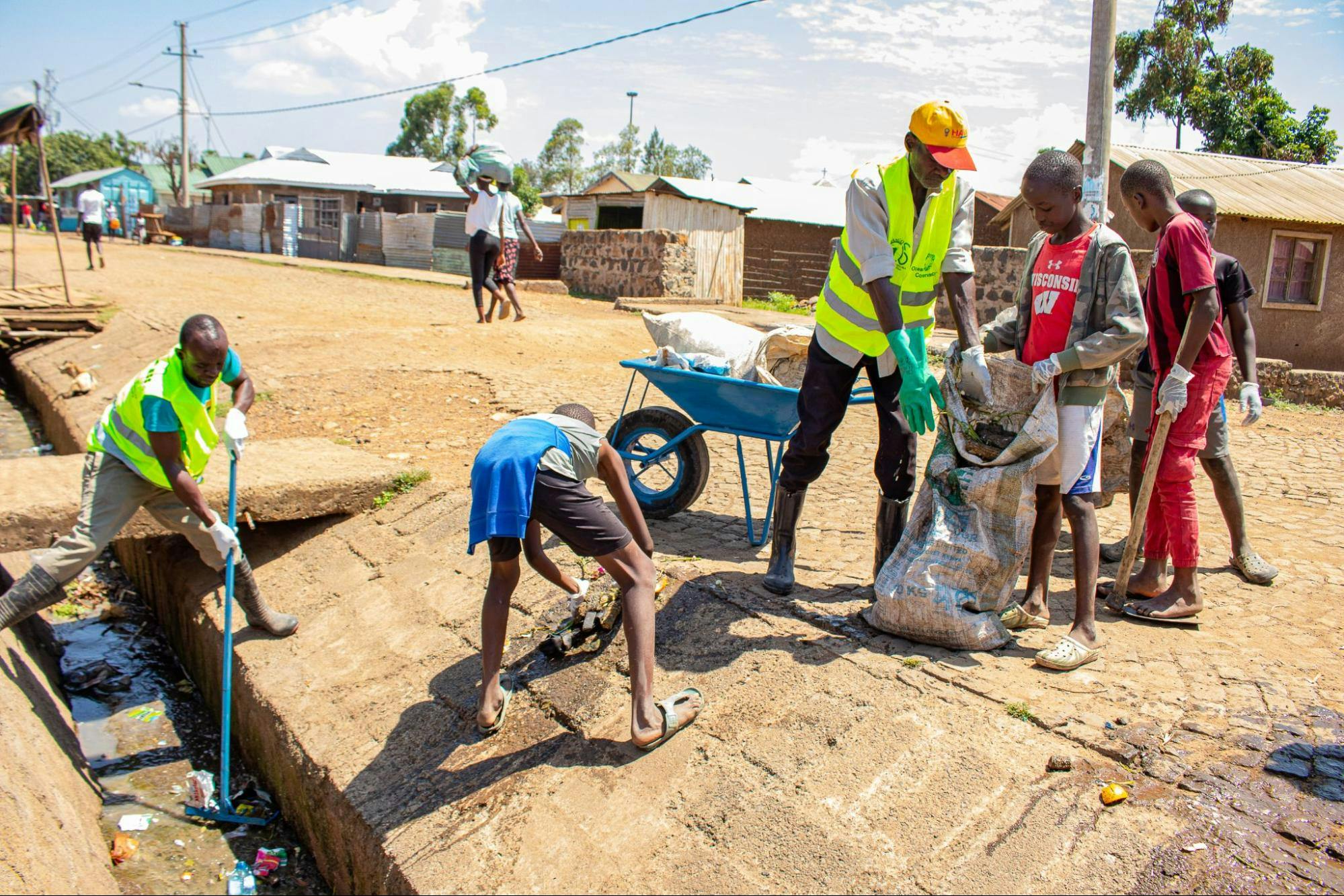 M-taka agents collecting waste from a trench with the help of the community